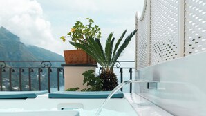 Un espace piscine aménagé sur le toit, agrémenté d’un élément décoratif aquatique, de plantes en pot et offrant une vue sur les montagnes.