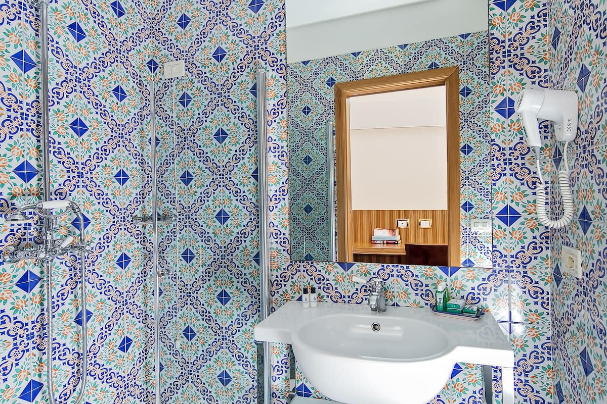 A bathroom with a white sink, a mirror above it, and a shower area.