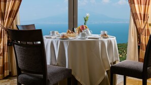 Une table à manger dressée avec un vase de fleurs, des croissants et une théière, offrant une vue panoramique.