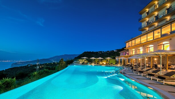 Une piscine avec vue sur la mer et un immeuble doté de balcons.