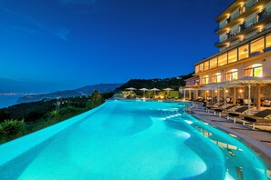 A swimming pool with a view of the sea and a building with balconies. - Grand Hotel Due Golfi (Massa Lubrense)