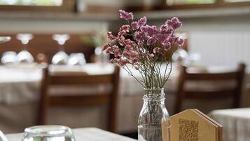 A dining table with a QR code menu, a vase with flowers, and cutlery.