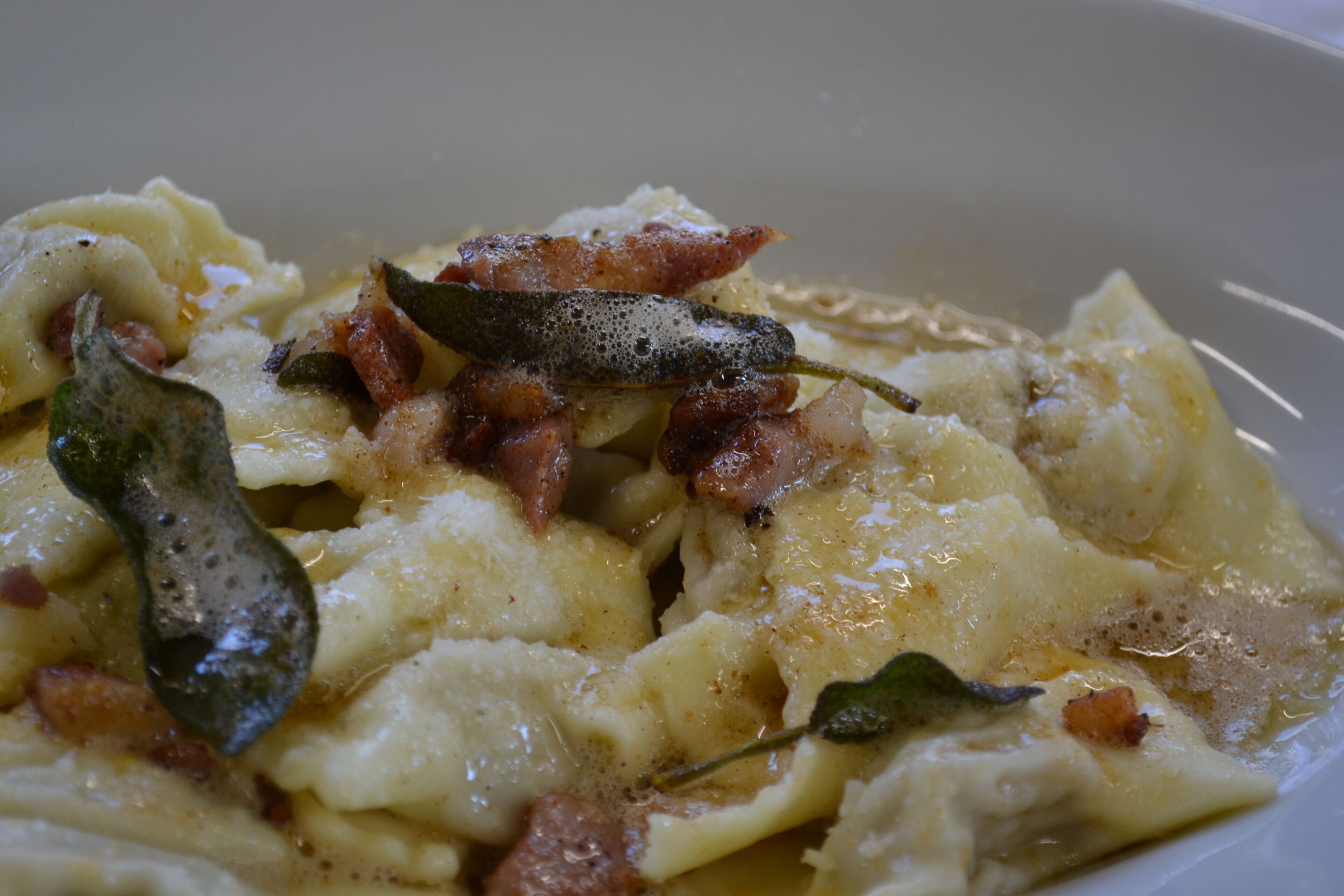 Primer plano de un plato de pasta cremosa con tocino y hierbas.