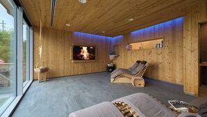 A wooden interior with a fireplace, a reclining chair, and a television. - Albergo Moderno (Fuipiano Valle Imagna)