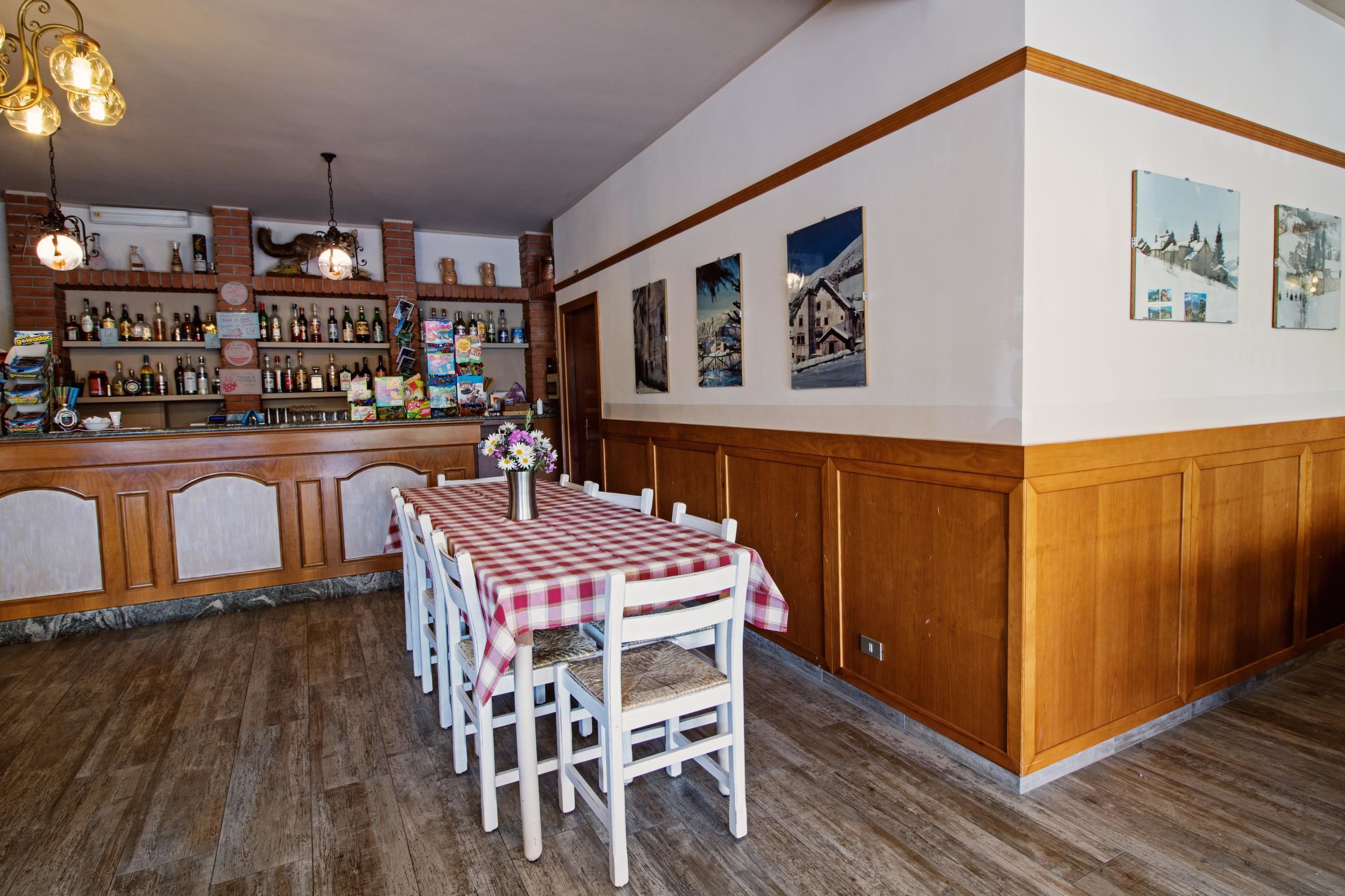 L’intérieur d’un restaurant avec un coin bar, des lambris en bois et une table recouverte d’une nappe à carreaux.