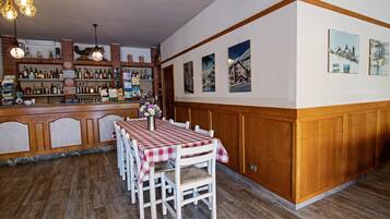 L’intérieur d’un restaurant avec un coin bar, des lambris en bois et une table recouverte d’une nappe à carreaux.