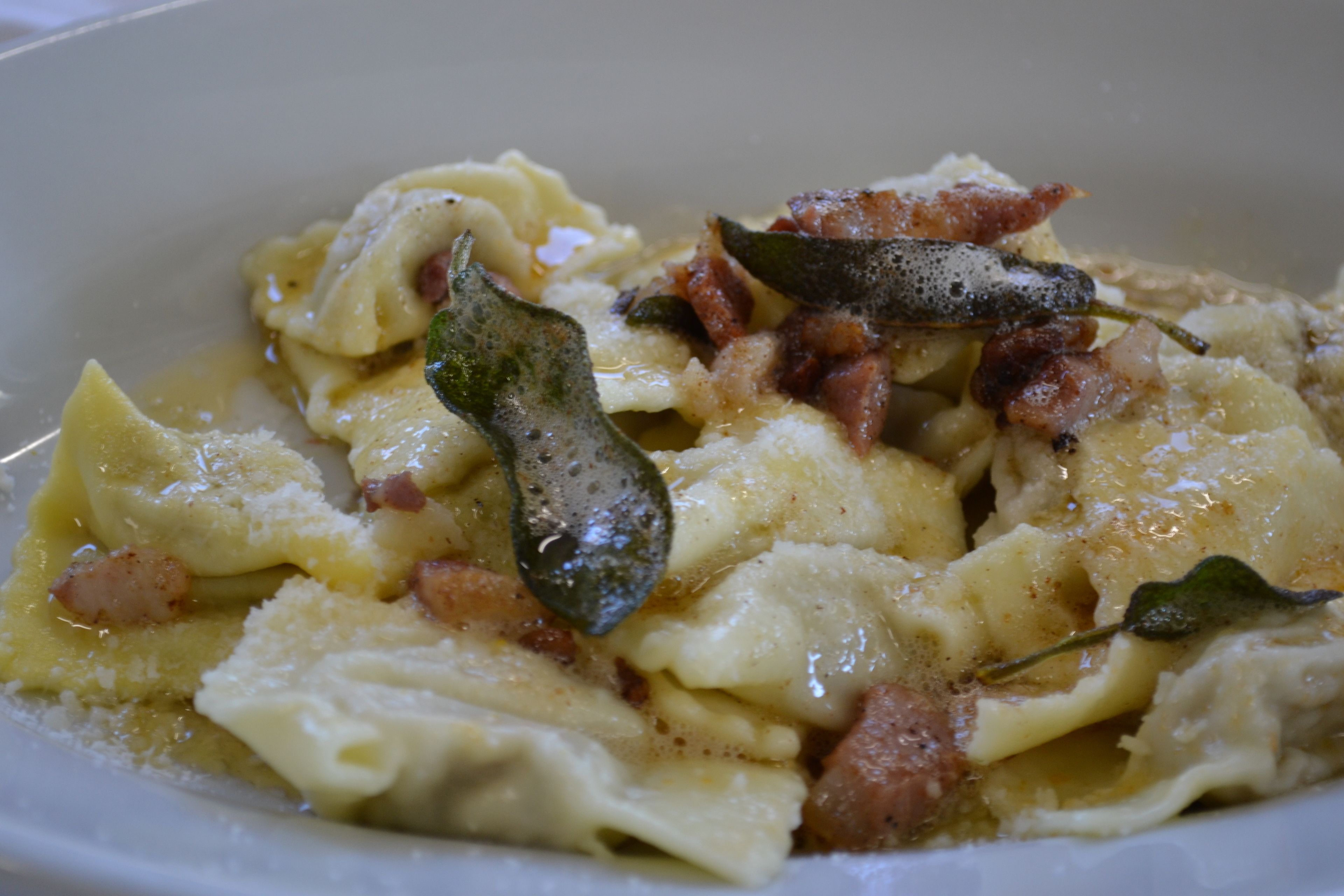 Un plato de pasta con queso y tocino, decorado con una hoja de laurel.