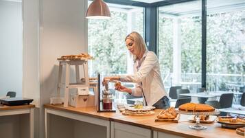 A person preparing food at a counter with various pastries and condiments.