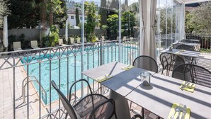 Zona junto a la piscina con mesa y sillas, barandilla de metal y vista a una piscina.
