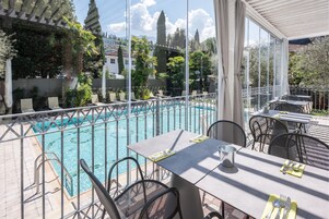 Una piscina al aire libre, sombrillas, sillones reclinables de piscina