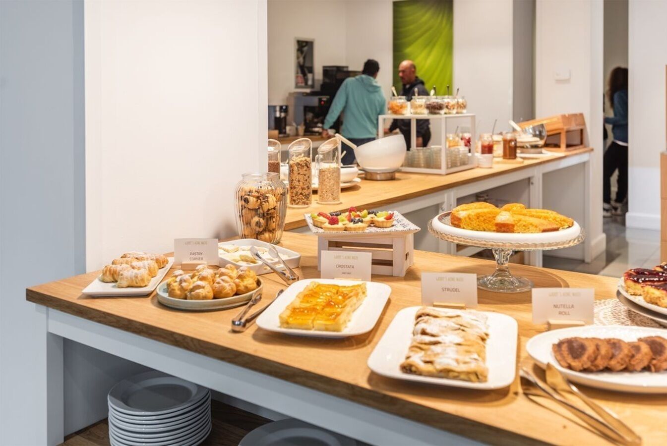 Un bufé con diversas pastelerías y postres, incluyendo croissants, strudel y un rollo de Nutella.