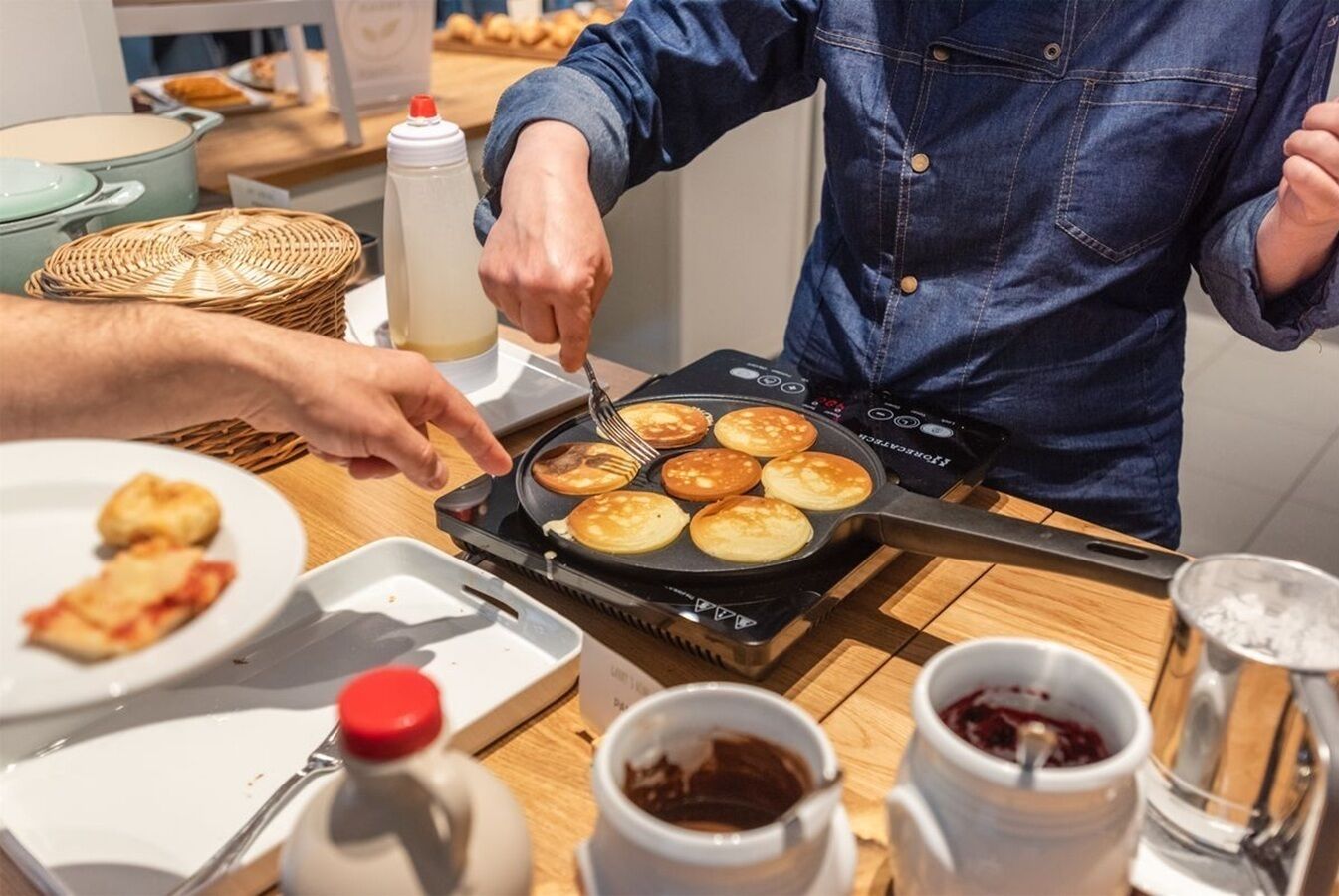Una persona cocinando tortitas en una plancha eléctrica portátil.