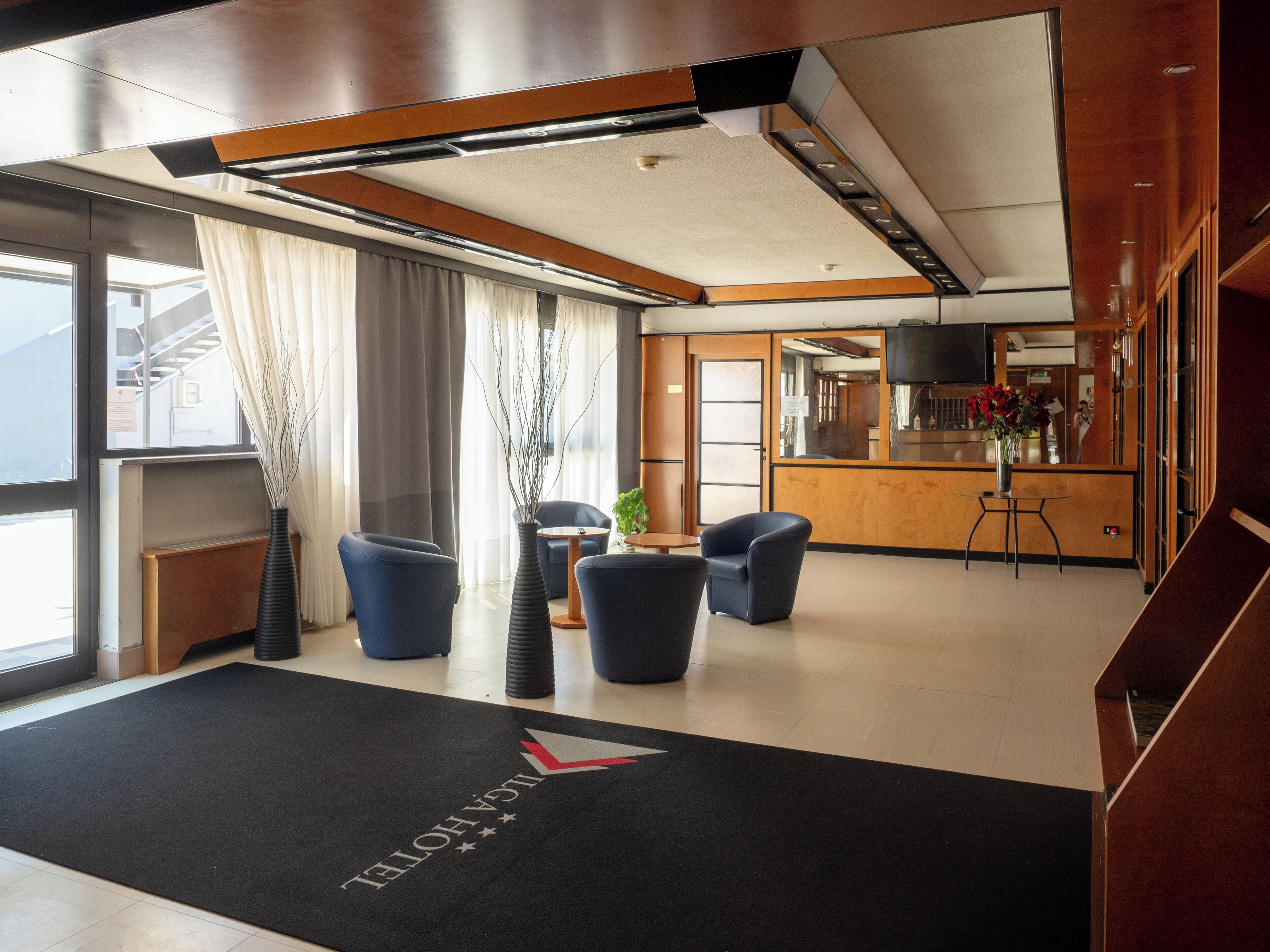 Un hall d’hôtel comprenant un comptoir d’accueil, un espace salon et une vue sur la cuisine.