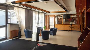 Un hall d’hôtel comprenant un comptoir d’accueil, un espace salon et une vue sur la cuisine.