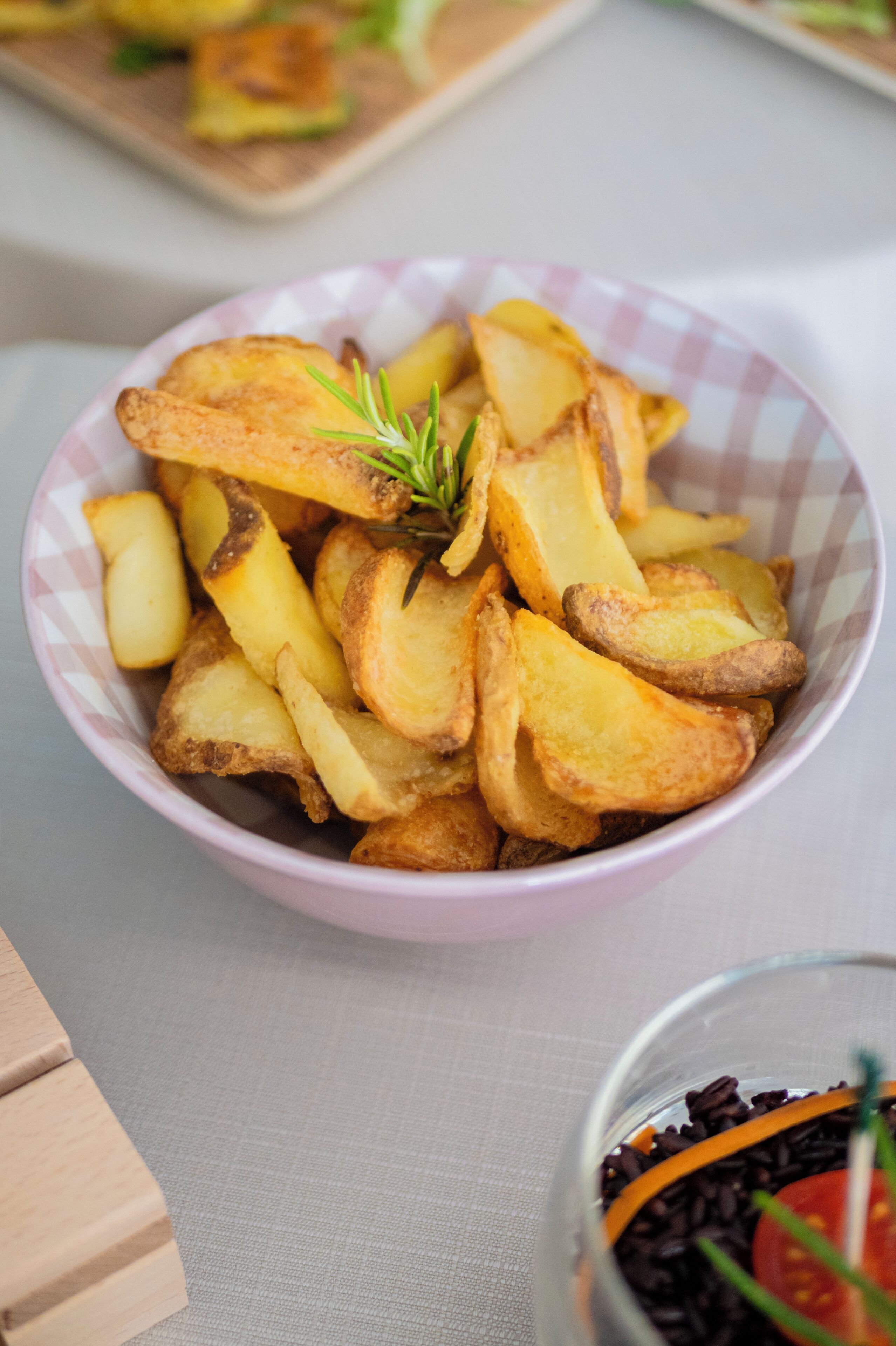 Un cuenco de papas asadas adornadas con romero.