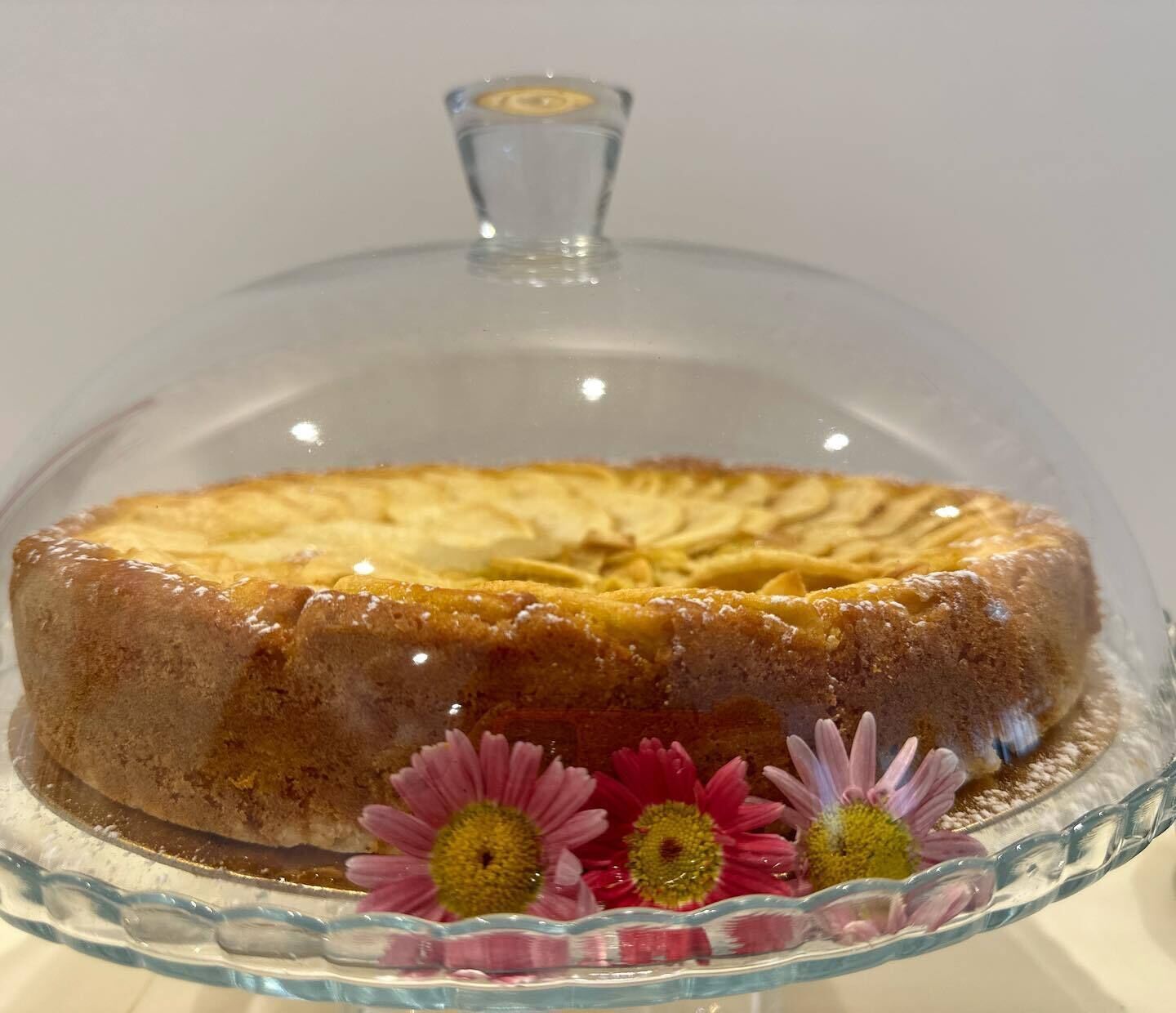 A cake on a glass stand with a clear dome cover.