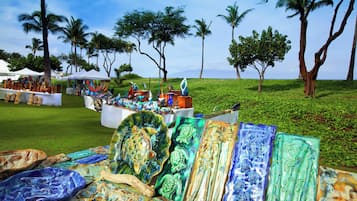 Un mercado frente a la playa con diversas piezas de arte de vidrio de colores expuestas sobre mesas.