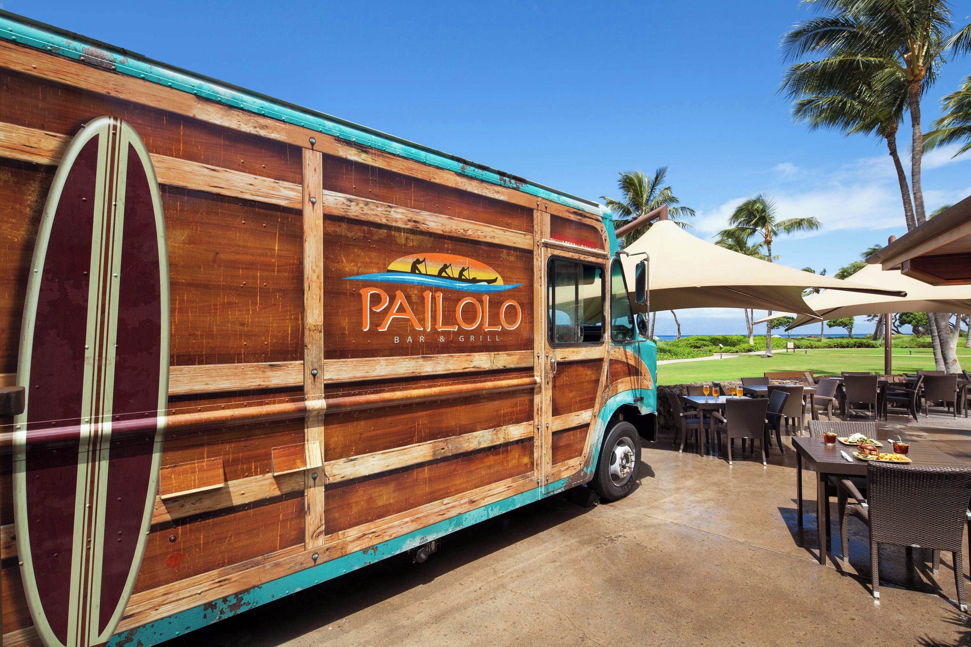 A PAILO Bar & Grill food truck parked at an outdoor dining area with tables and chairs.