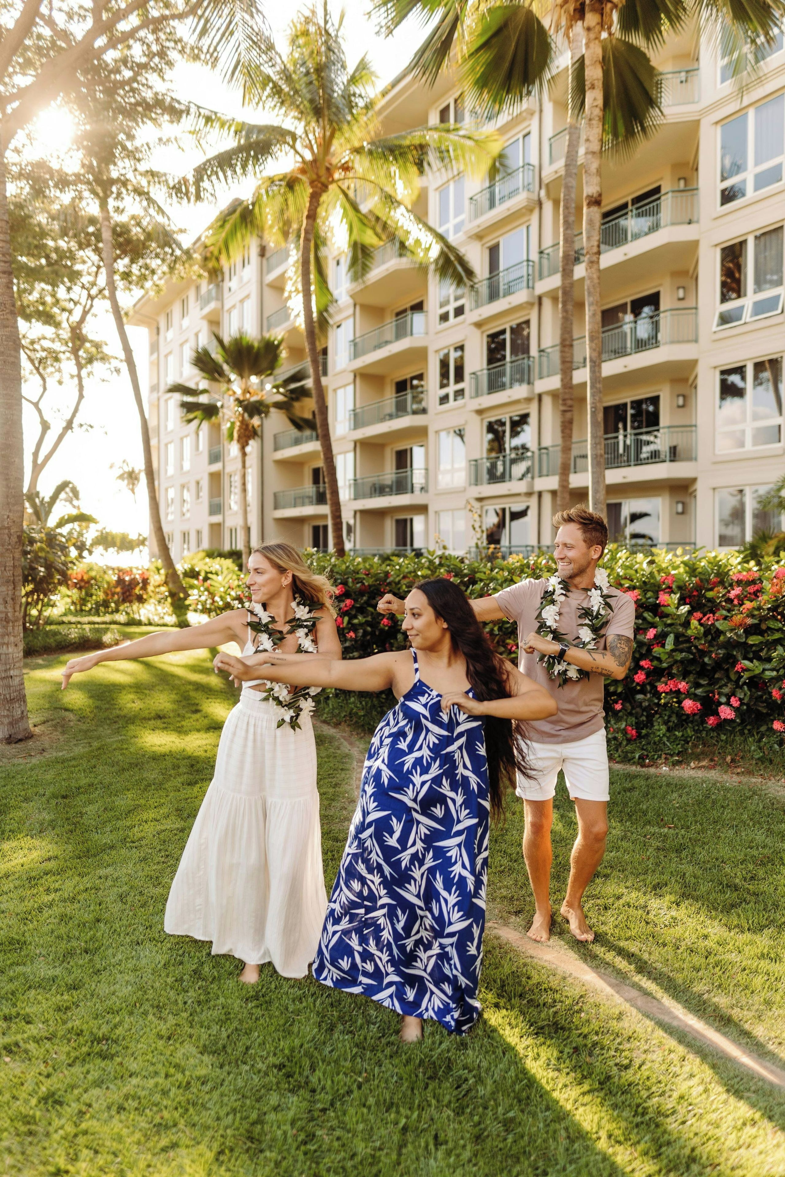 A hotel with a multi-story building, outdoor seating area, and lush greenery.