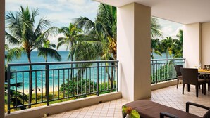 A balcony with a view of the ocean and palm trees, a dining area with chairs, and a small table with a vase of flowers. - The Westin Ka'anapali Ocean Resort Villas (Lahaina)
