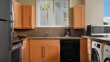 Una cocina con gabinetes de madera, lavavajillas, lavadora y cafetera.