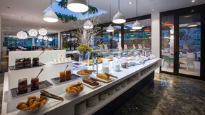 A buffet with various food items and a large window with a view of greenery. - Abora Catarina by Lopesan Hotels - All Inclusive (San Bartolomé de Tirajana)