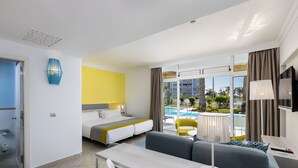 A modern hotel room with a bed, sofa, dining table, and a view of a swimming pool. - Abora Catarina by Lopesan Hotels - All Inclusive (San Bartolomé de Tirajana)