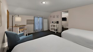 A hotel room with two beds, a desk with a chair, a small table, a TV, and a window with curtains. - Traverse Bay Inn (Traverse City)