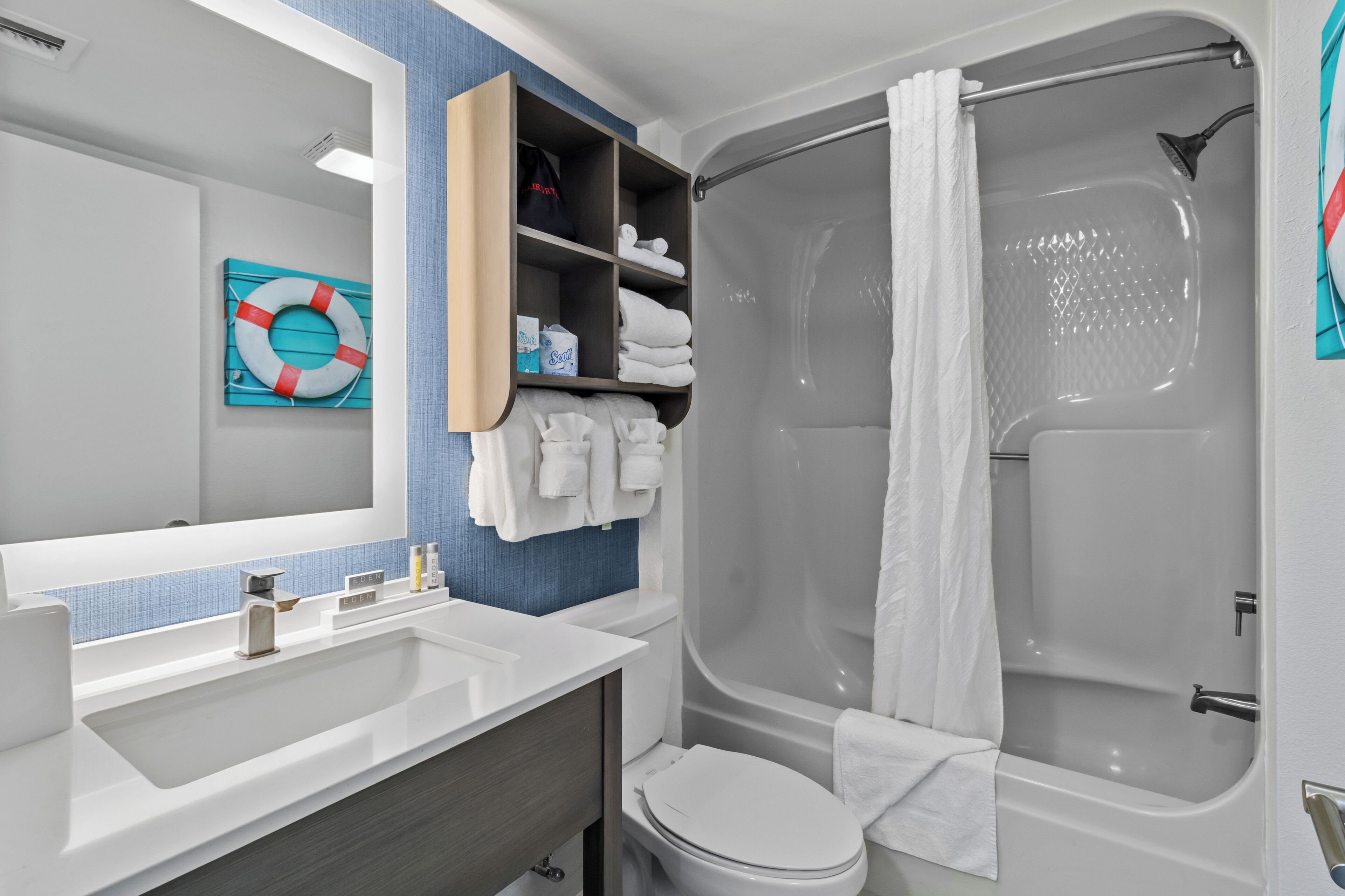 A modern bathroom with a white sink, a toilet, and a walk-in shower.