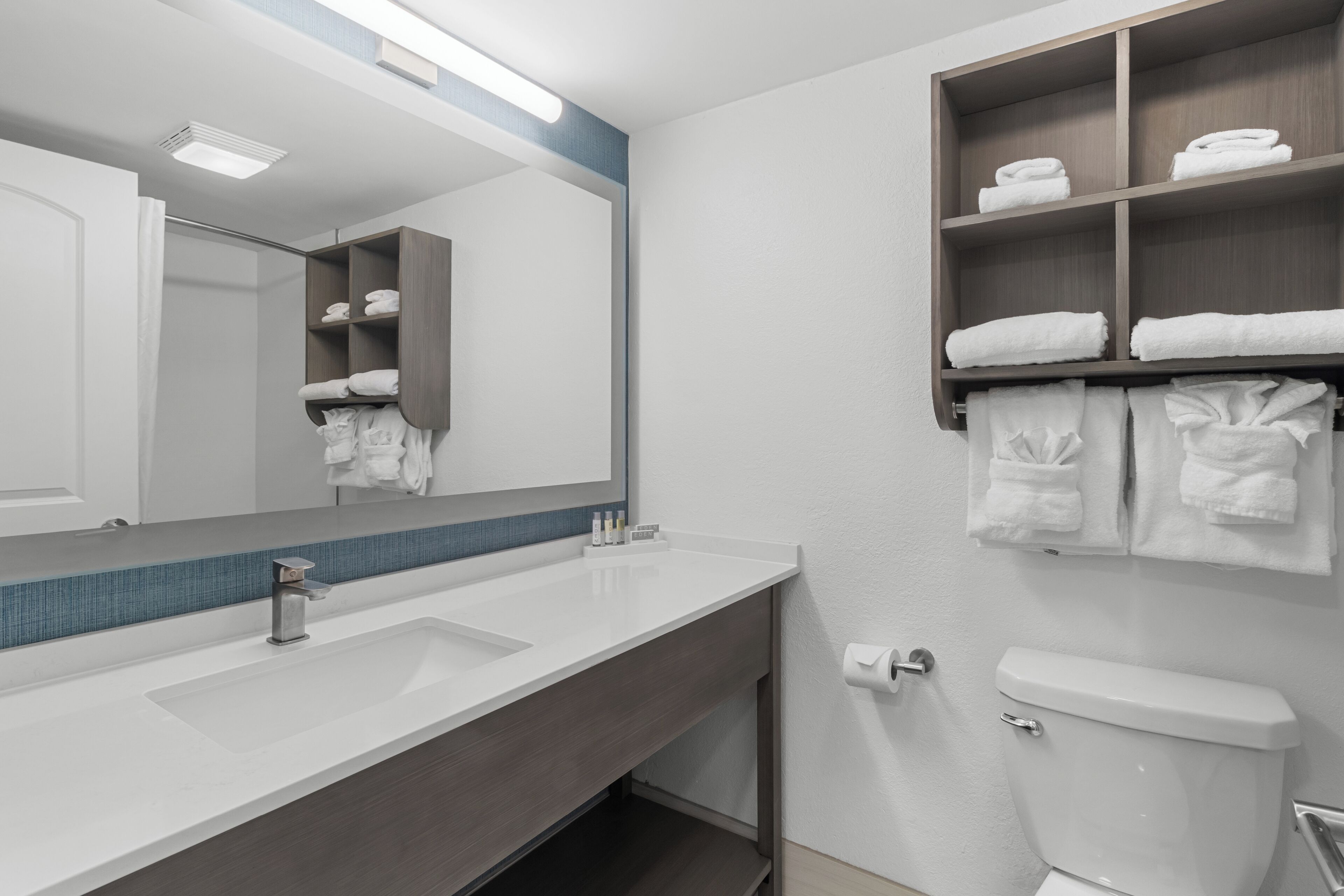 A modern bathroom with a white sink, a mirror, a towel rack, and a toilet.