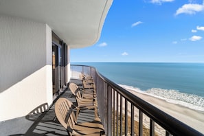 A balcony with rows of chairs facing the ocean.