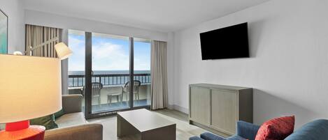 Een hotelkamer met een balkon, een flatscreen televisie, een zithoek en een bureau.