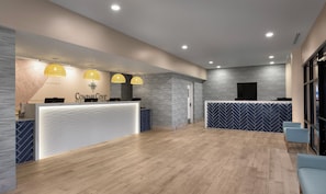 A reception area with a white reception desk, multiple pendant lights, and a large window.
