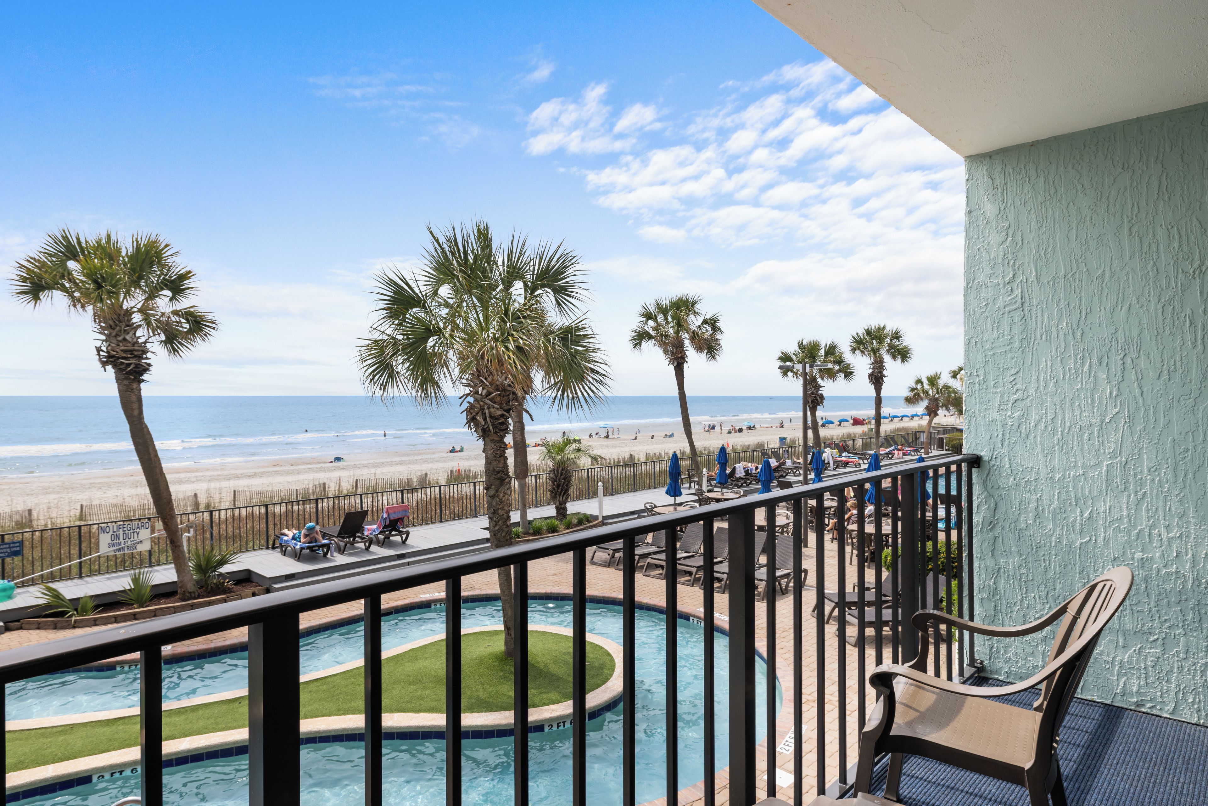 A pool area with a view of the beach and ocean.