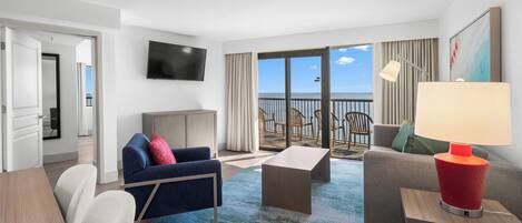 Une chambre d’hôtel moderne dotée d’un balcon, d’un téléviseur à écran plat, d’un canapé, d’une table basse et d’une lampe.