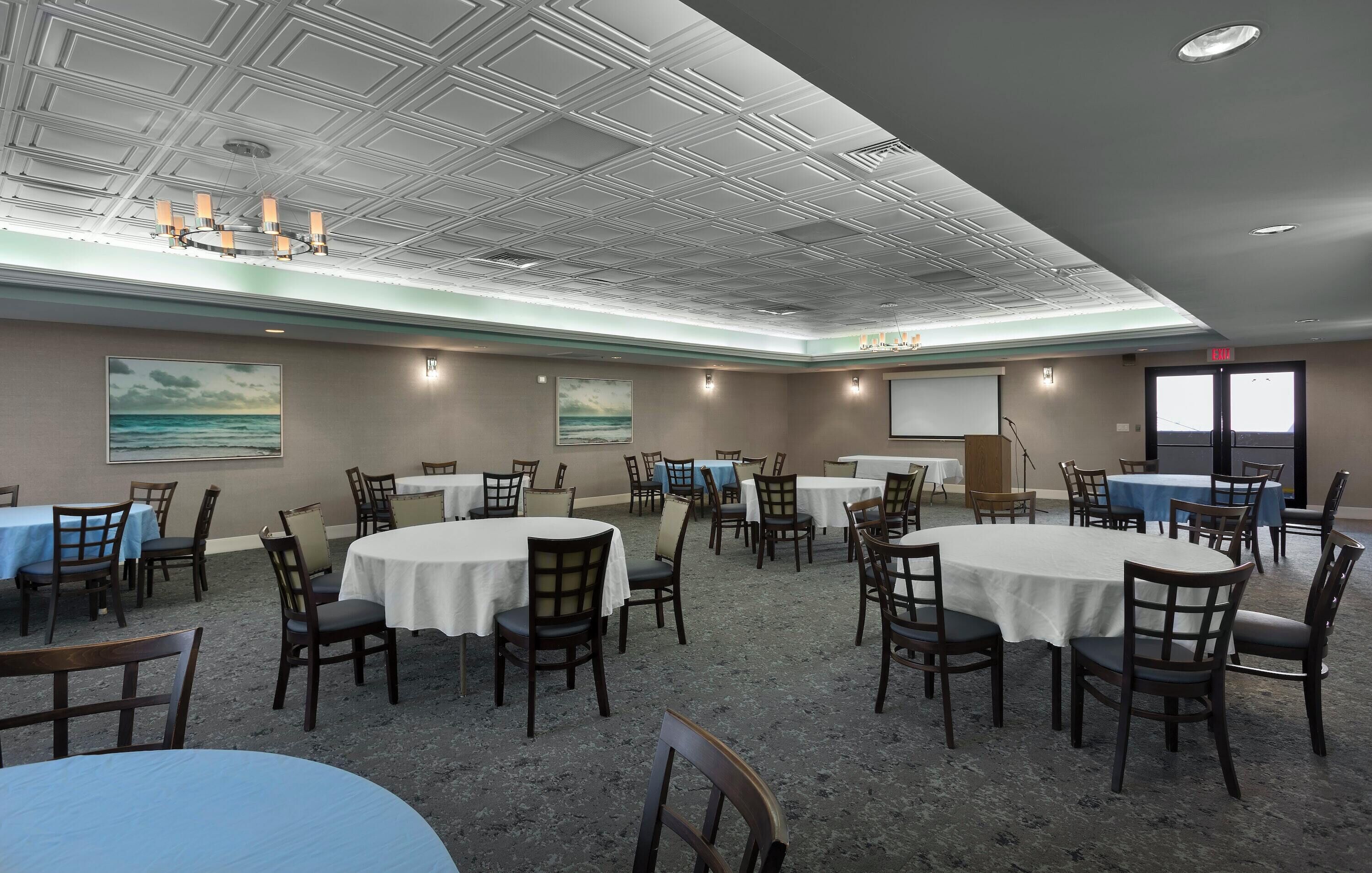 A conference room with round tables and chairs, a projector, and a screen.