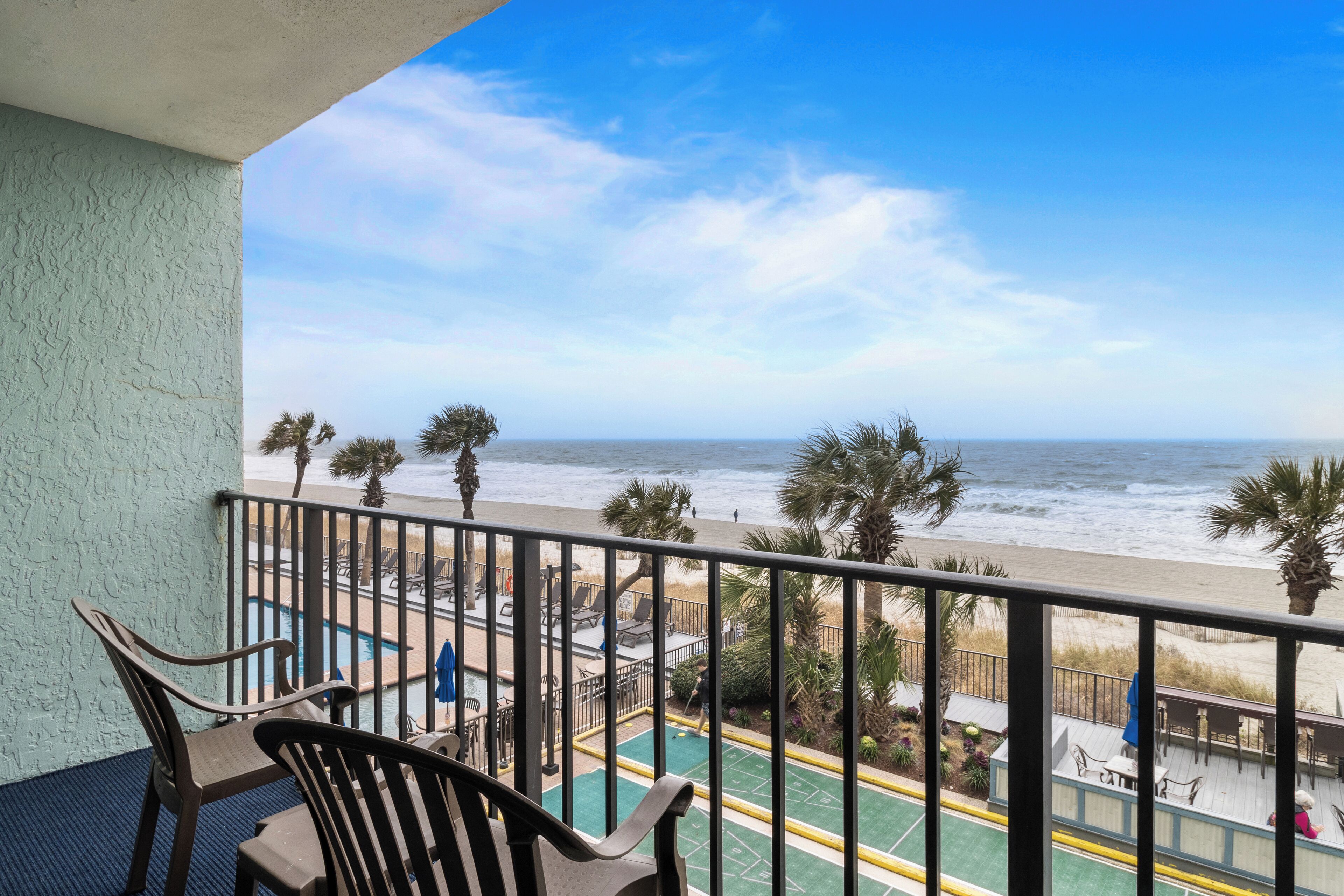 A balcony with a view of the beach and ocean.