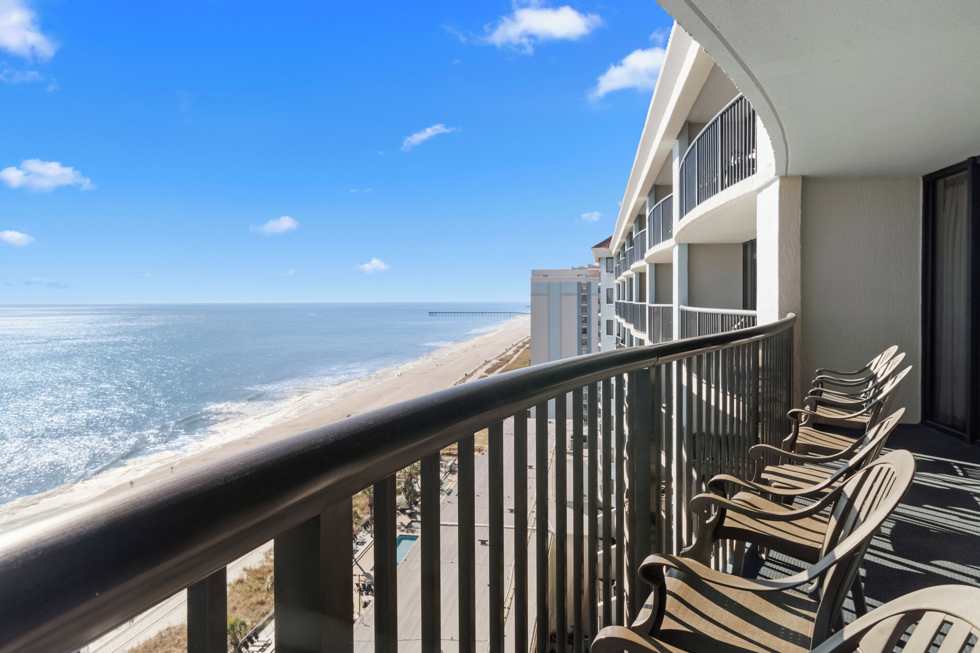 A balcony with a view of the beach and ocean.
