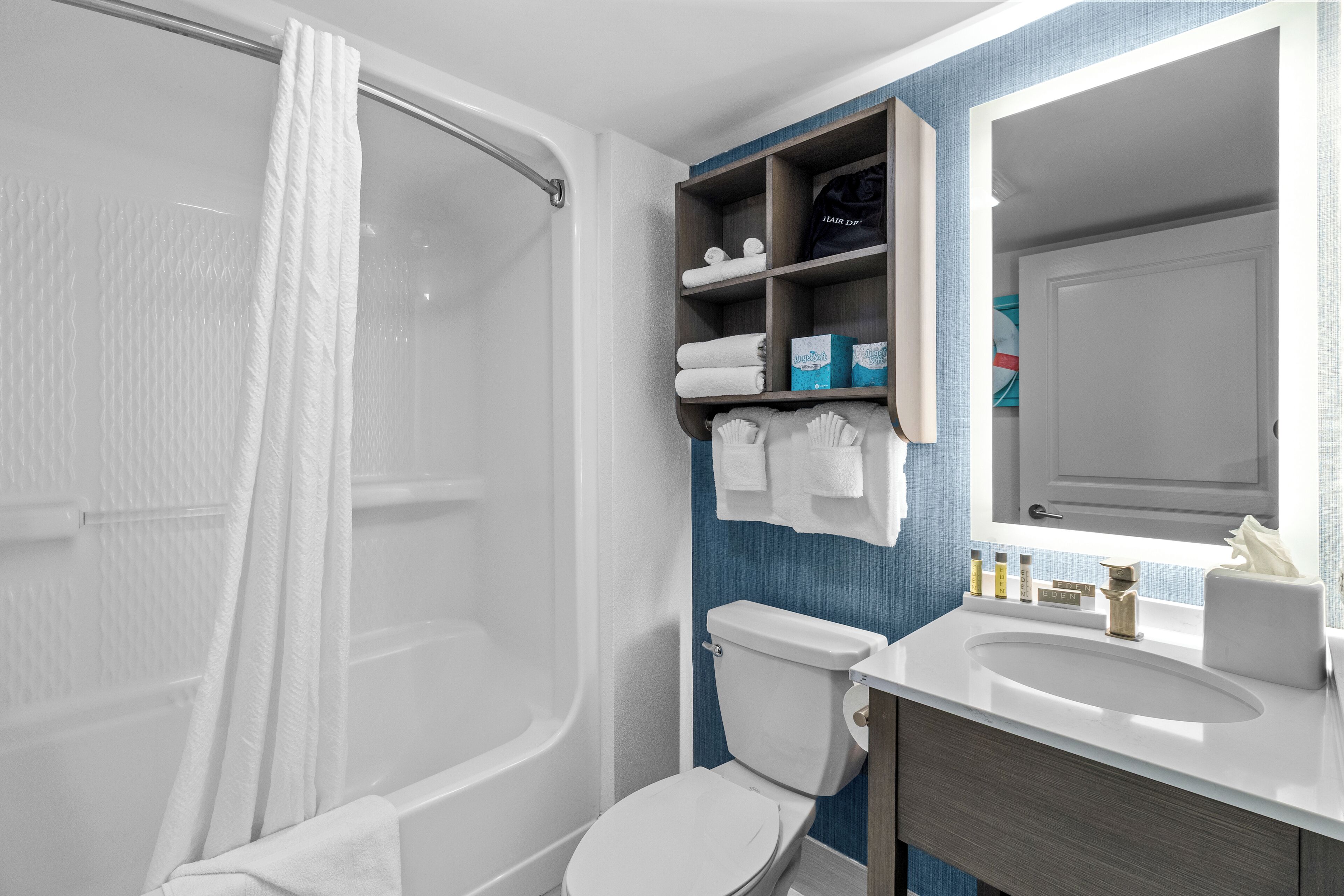 A modern bathroom with a bathtub, toilet, and vanity with a mirror.