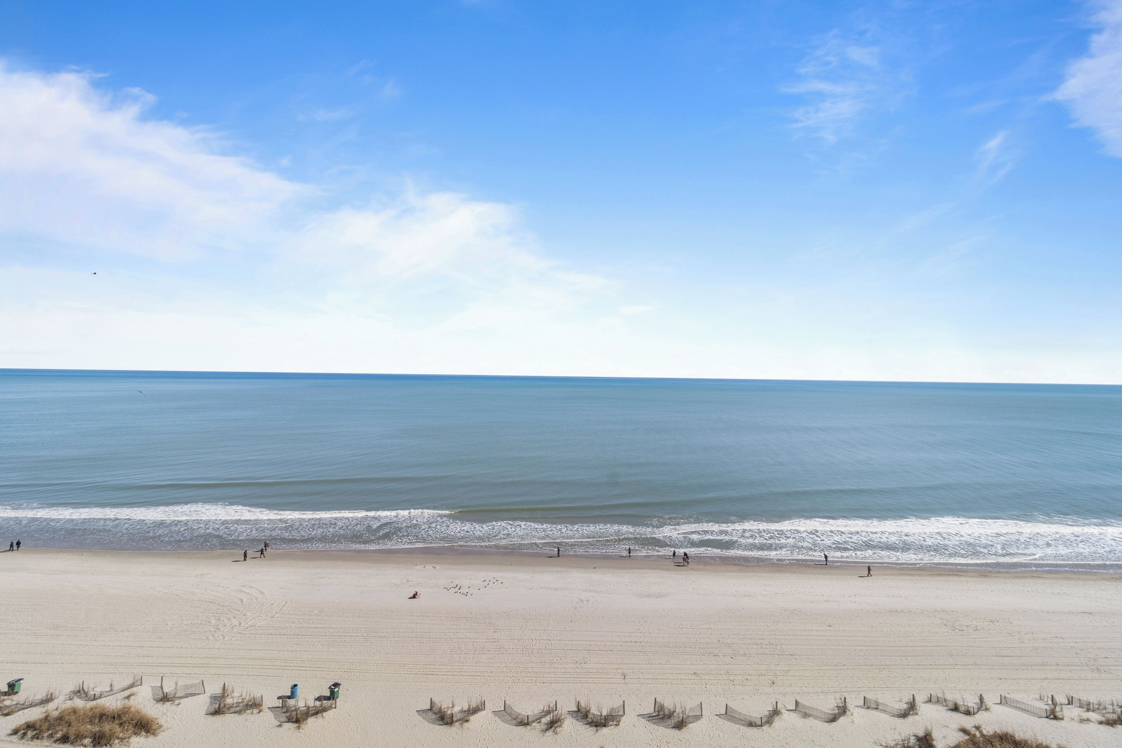A beach with a clear sky, calm sea, and a sandy shore.