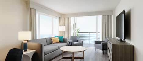 A modern hotel room with a grey sofa, a round coffee table, a TV, and a balcony with a railing.
