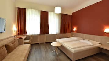 Una habitación de hotel con una cama, un sofá, una mesita, un escritorio y un televisor.