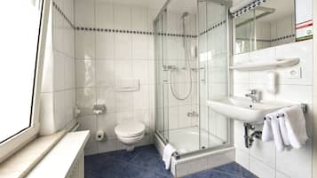 A modern bathroom with a glass-enclosed shower, a white sink, and a toilet.