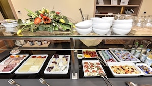 A buffet with various food items and utensils. - Hotel ADRIA München (Munich)