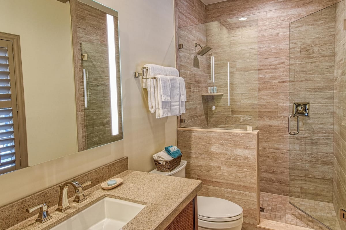 A bathroom with a vanity, a toilet, and a glass-enclosed shower area.