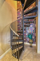 A spiral staircase with a metal railing leading to a bookshelf filled with books.