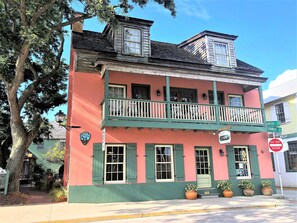 A two-story building with a balcony, green shutters, and a sign indicating 'City of Charleston Historic District'.