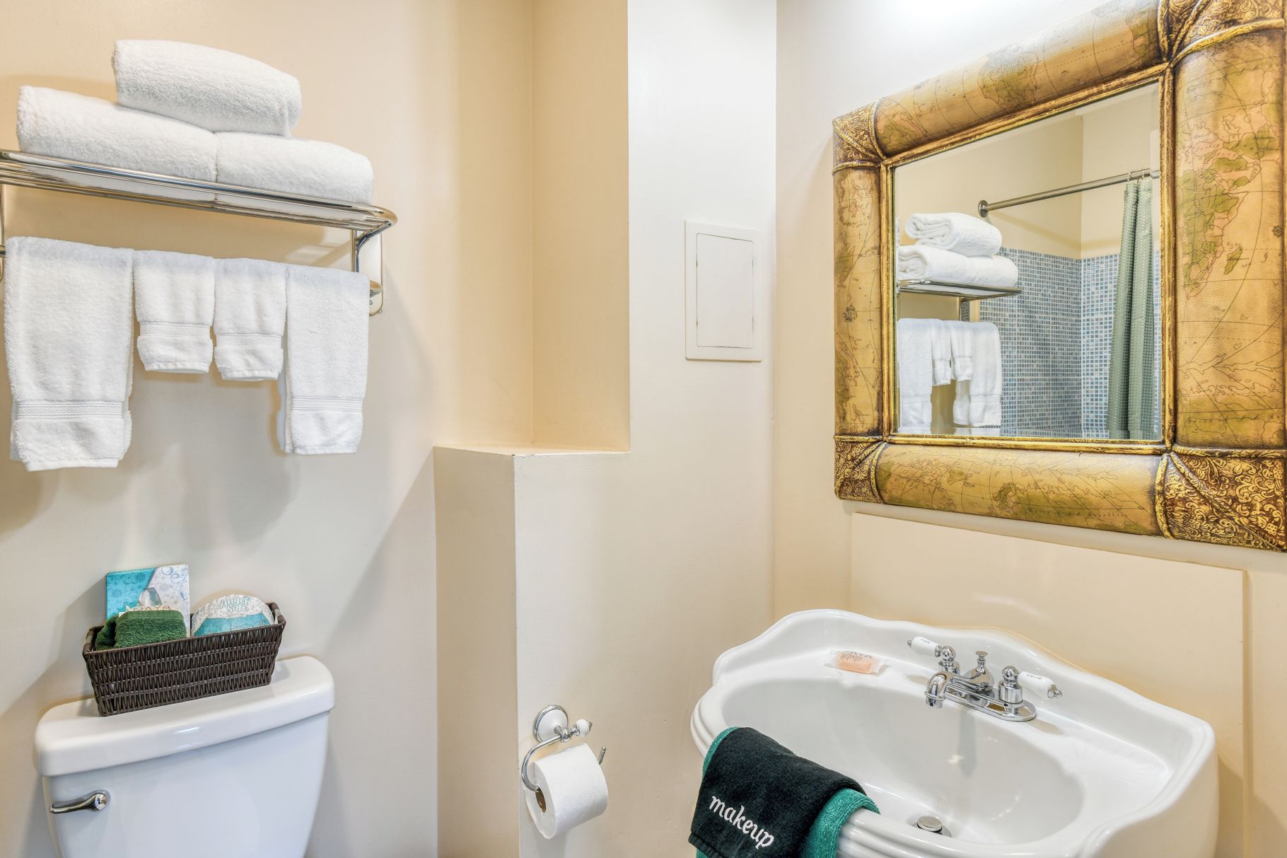 A bathroom with a toilet, sink, and a mirror with a decorative frame.