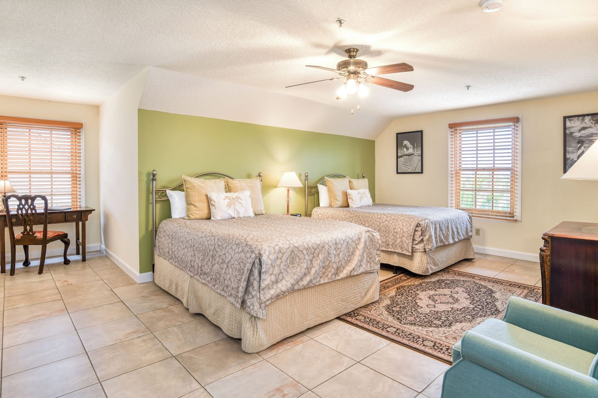 A bedroom with two beds, a desk, and a chair.