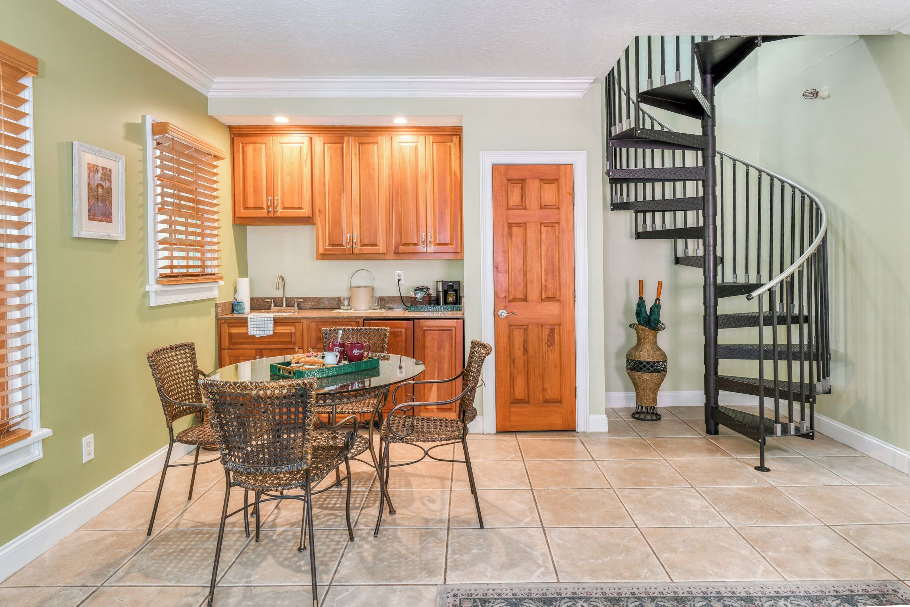 A kitchen with wooden cabinets, a dining table with chairs, and a spiral staircase.